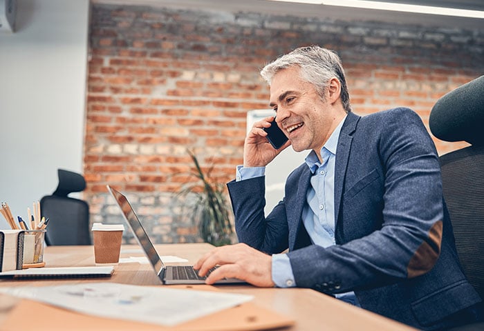 A founder wearing a formal outfit on a phone call with a happy expression.