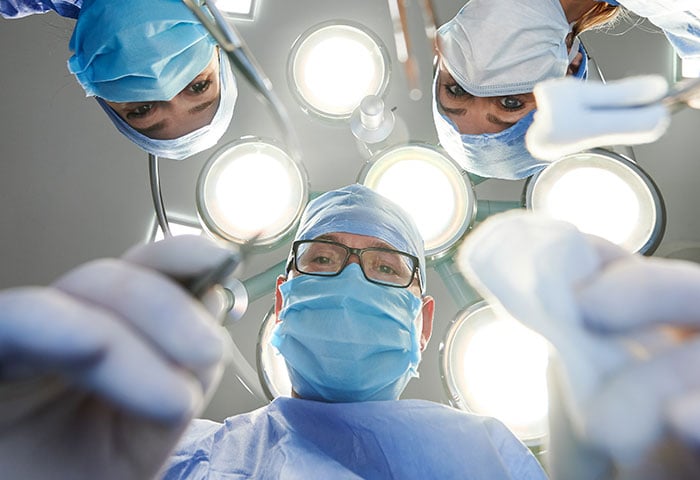 一群医疗专业人员俯视着病人，图像是从病人的角度看的。